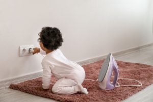 Little,African-american,Baby,Playing,With,Socket,And,Iron,At,Home.